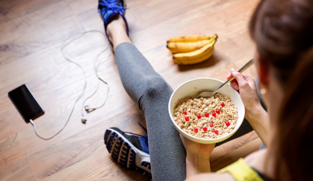 Girl in gym clothes eating a bowel of oatmeal