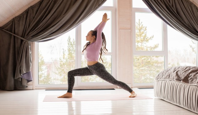 women doing yoga pose in front of her bedroom window